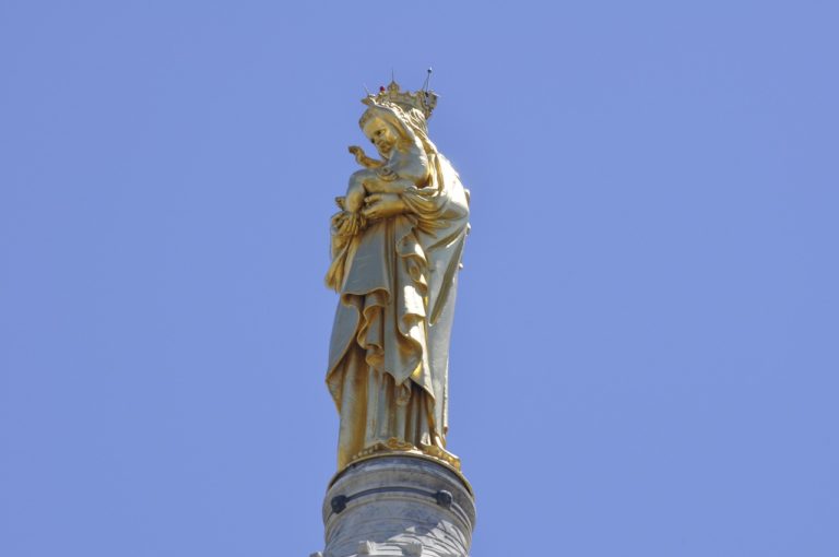 Golden statue atop Notre-Dame de la Garde Basilica against a clear blue sky in Marseille, France.