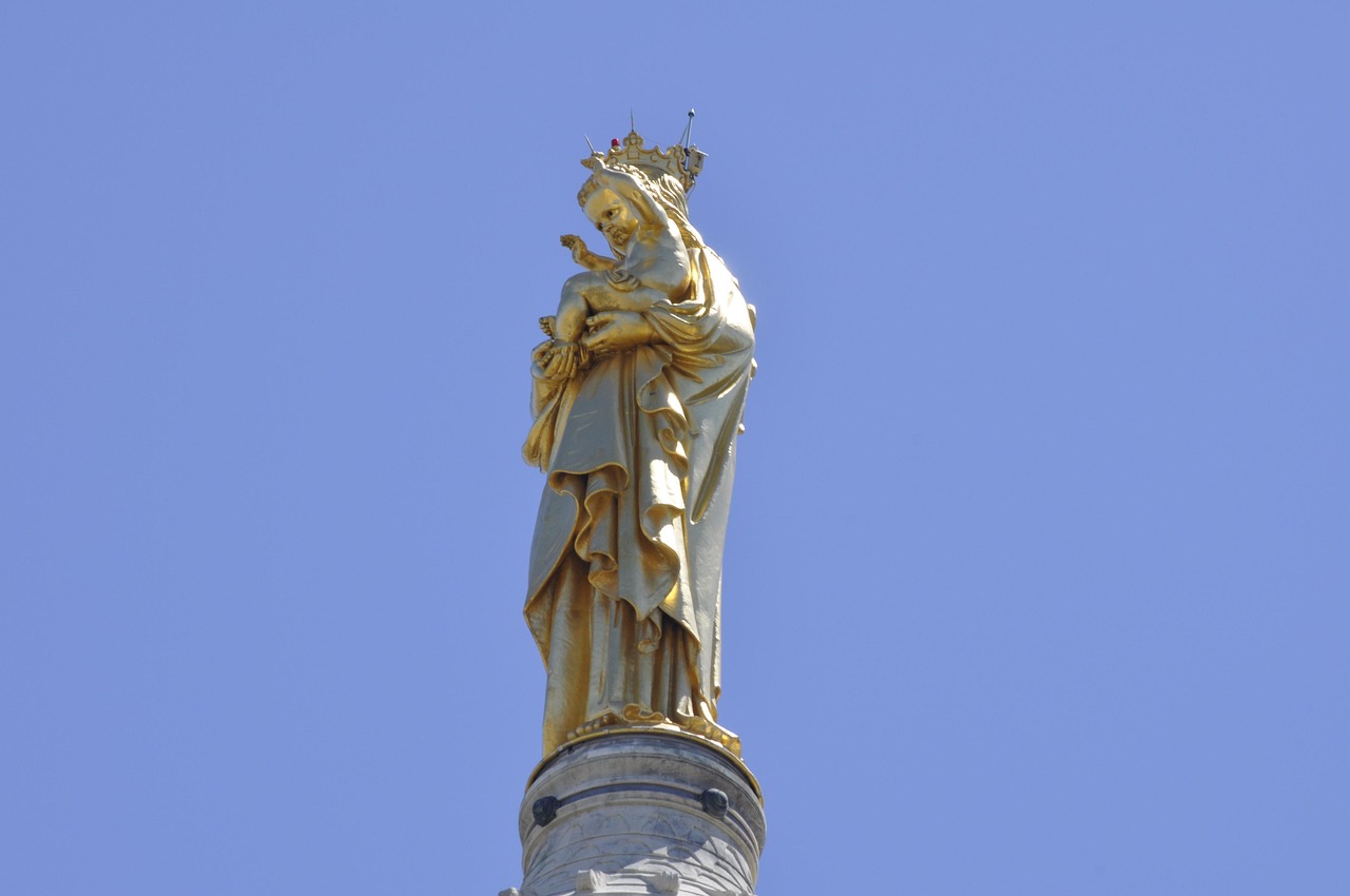 Golden statue atop Notre-Dame de la Garde Basilica against a clear blue sky in Marseille, France.